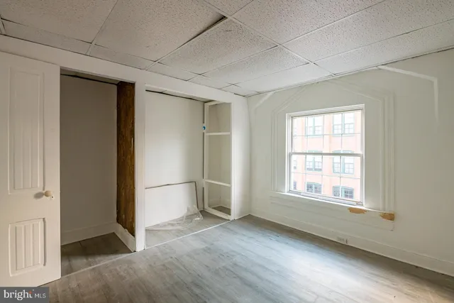 an empty room with wooden floor cabinet and windows
