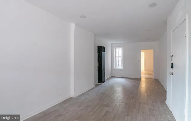 a view of an empty room with window and wooden floor