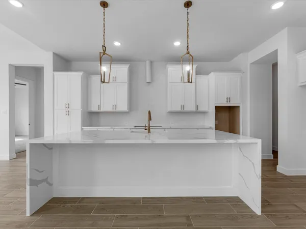a large kitchen with granite countertop a sink a counter top space and cabinets