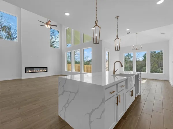 a large white kitchen with kitchen island a large window a sink and a chandelier