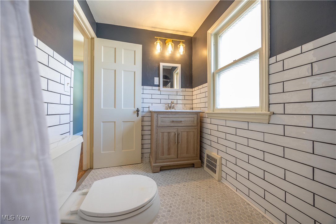 3797 Northwood Road Cleveland, OH 44118 - Photo 29 of 49 Bathroom with vanity, tile walls, light tile patterned floors, and wainscoting