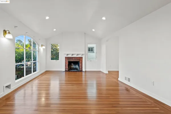 a view of empty room with wooden floor and fireplace