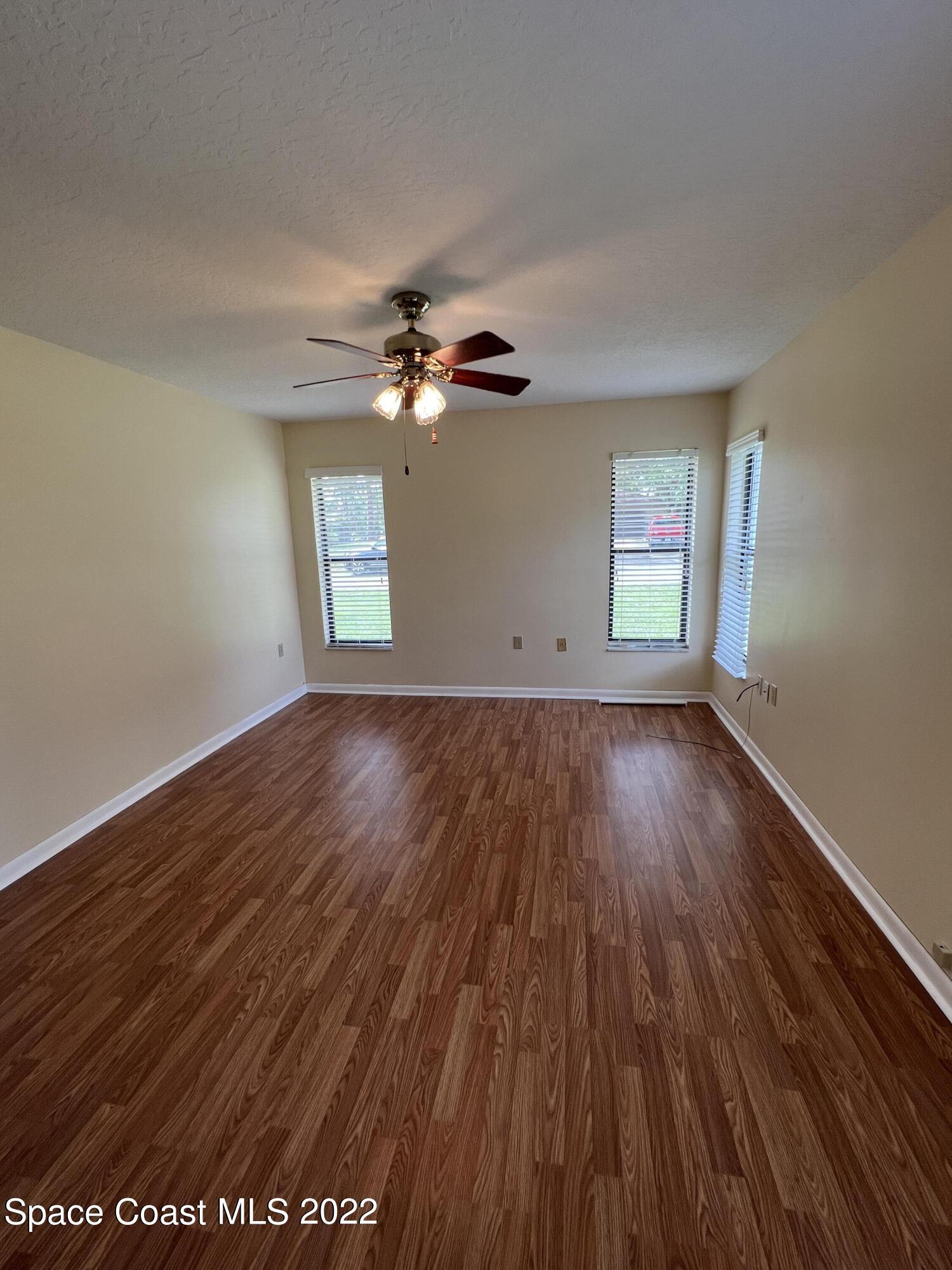4897 Bridge Road Cocoa, FL 32927 - Photo 9 of 12 an empty room with wooden floor chandelier fan and windows