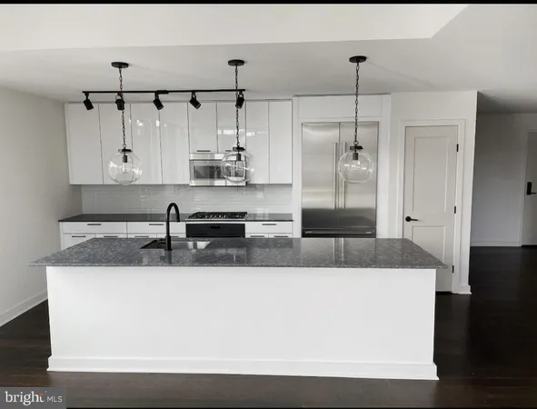 a large kitchen with granite countertop a sink and white cabinets