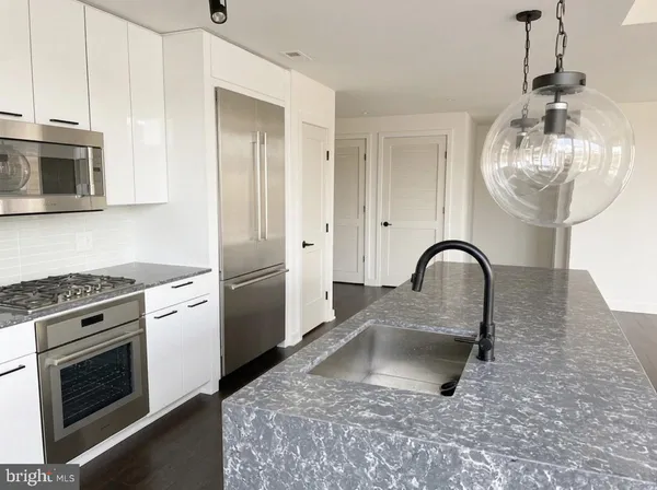 a kitchen with stainless steel appliances granite countertop a sink a stove a refrigerator cabinets and a dining table