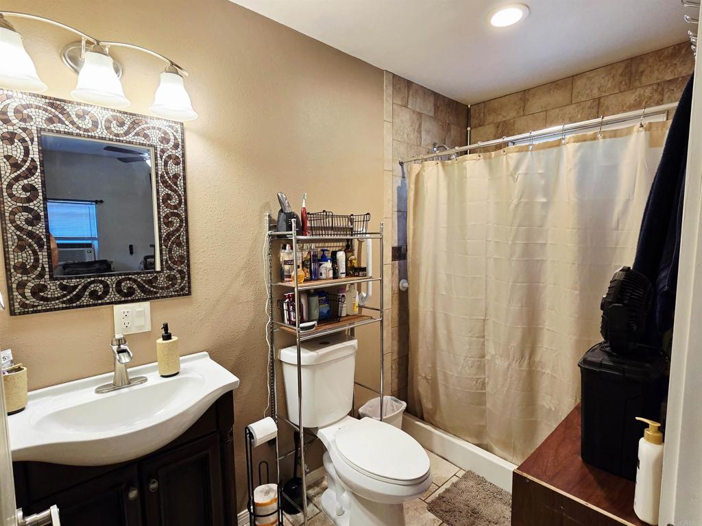 9690 Bundy Drive Santee, CA 92071 - Photo 52 of 66 a bathroom with a sink a toilet a mirror and shower curtain