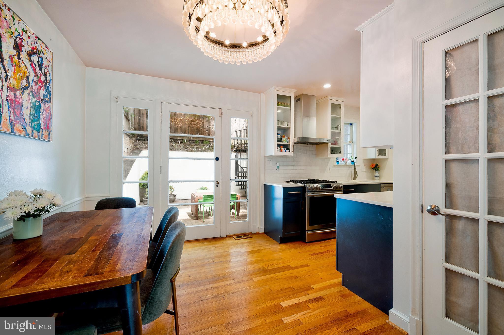 2135 Tunlaw Road Northwest Washington, DC 20007 - Photo 10 of 48 a kitchen with stainless steel appliances kitchen island granite countertop a table chairs in it and wooden floors