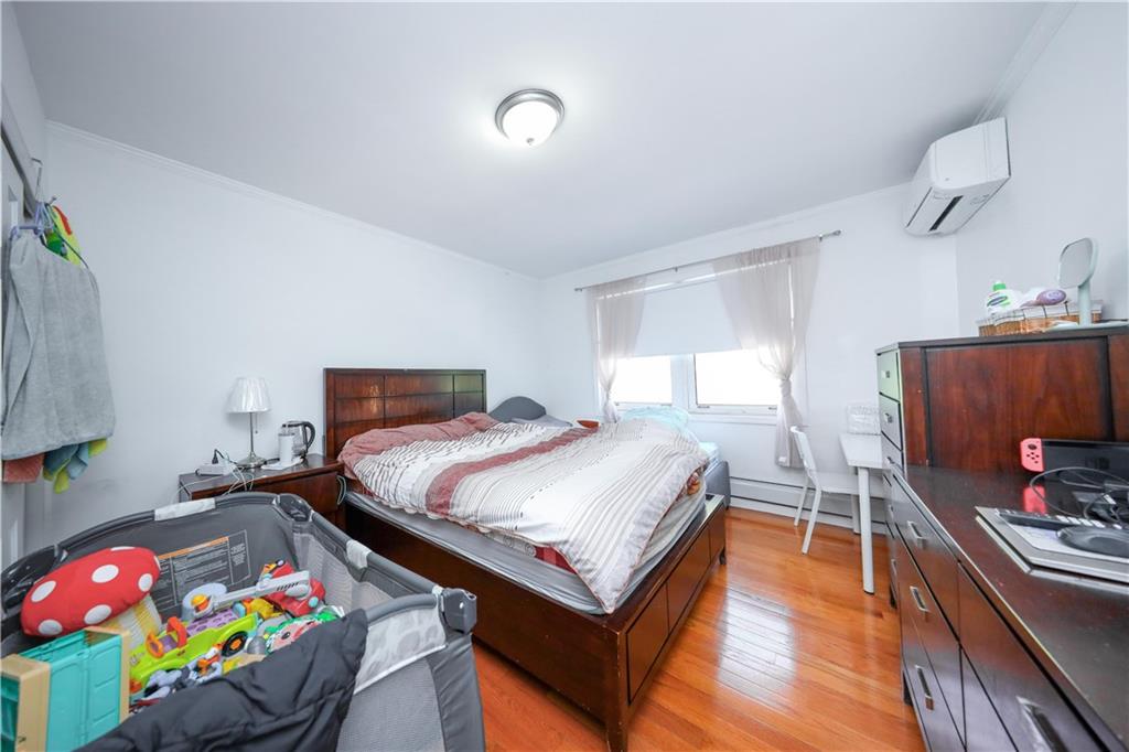 2046 Stuart Street Brooklyn, NY 11229 - Photo 13 of 27 a bedroom with a bed and a dresser with wooden floor