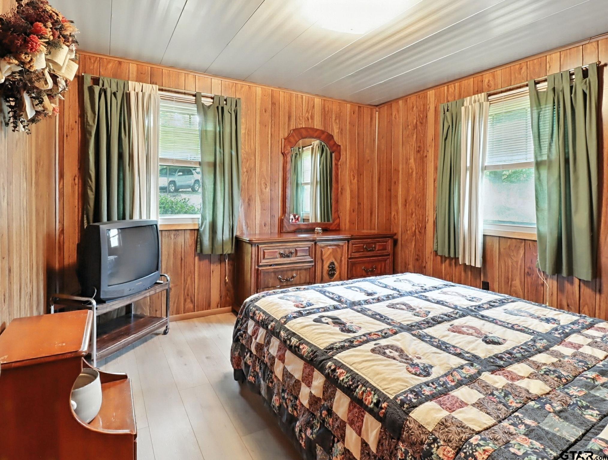 402 Watson Road Gladewater, TX 75647 - Photo 20 of 32 a bedroom with a bed dresser and a flat tv screen next to a window