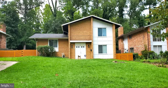 a front view of a house with a yard and trees