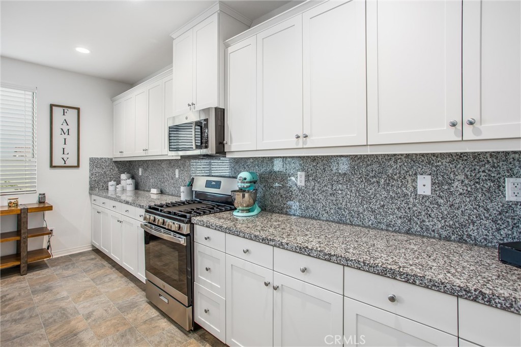 14019 Dandolo Lane Beaumont, CA 92223 - Photo 9 of 34 a kitchen with granite countertop white cabinets and stainless steel appliances