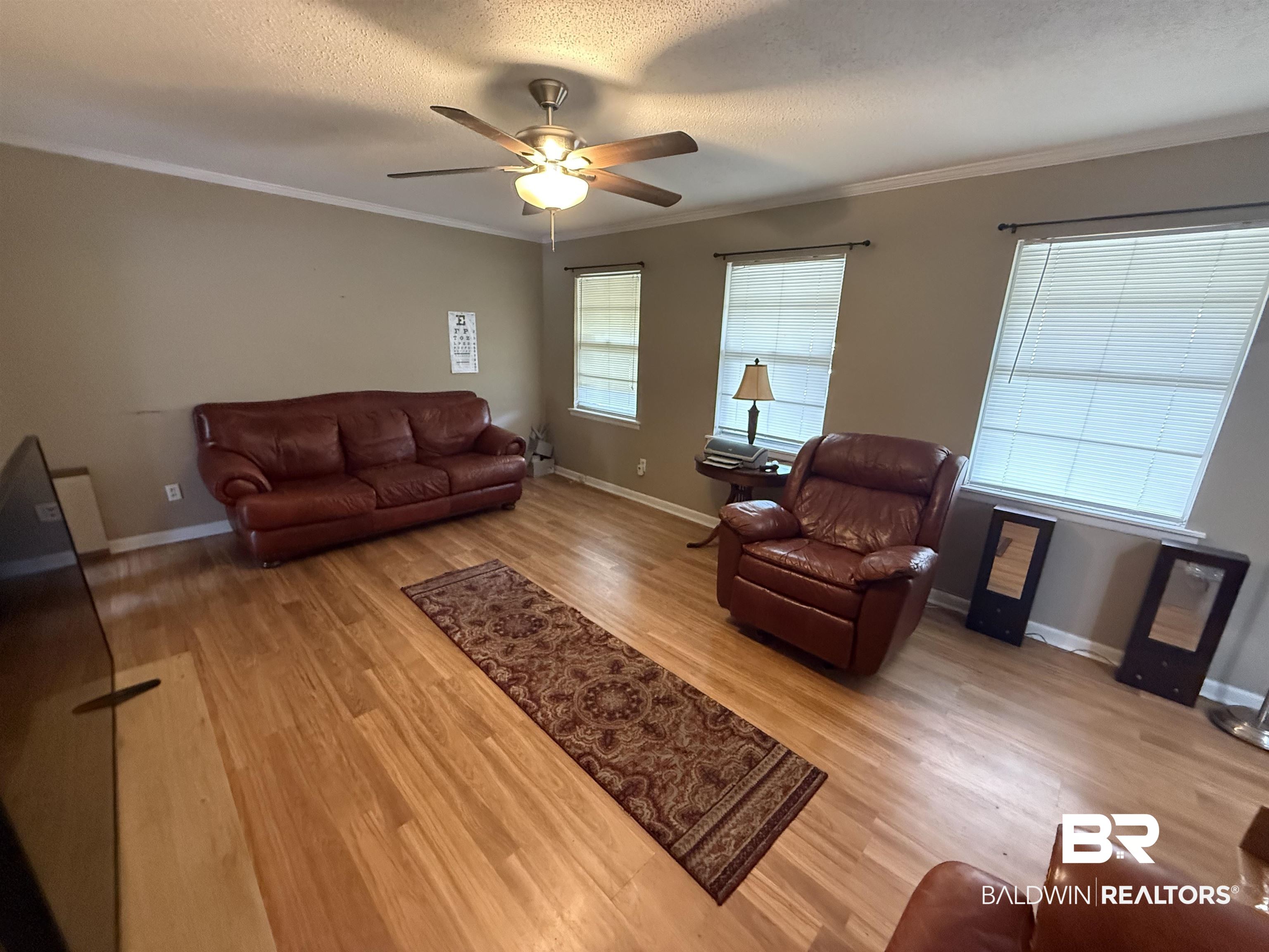 2807 Pea Ridge Road Brewton, AL 36426 - Photo 4 of 12 Living room with crown molding, light wood-style floors, a textured ceiling, and a ceiling fan