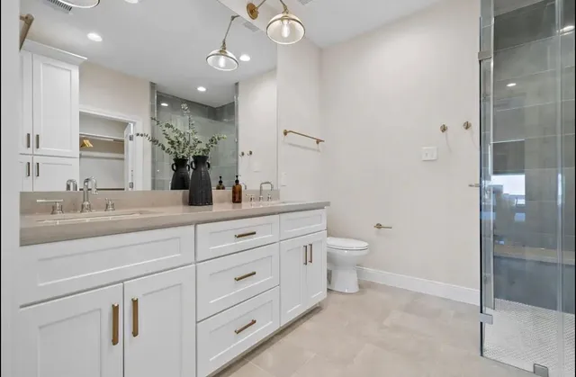 a bathroom with a granite countertop sink a toilet and a large mirror