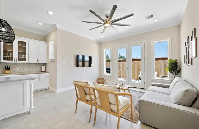 a living room with furniture a ceiling fan and a large window