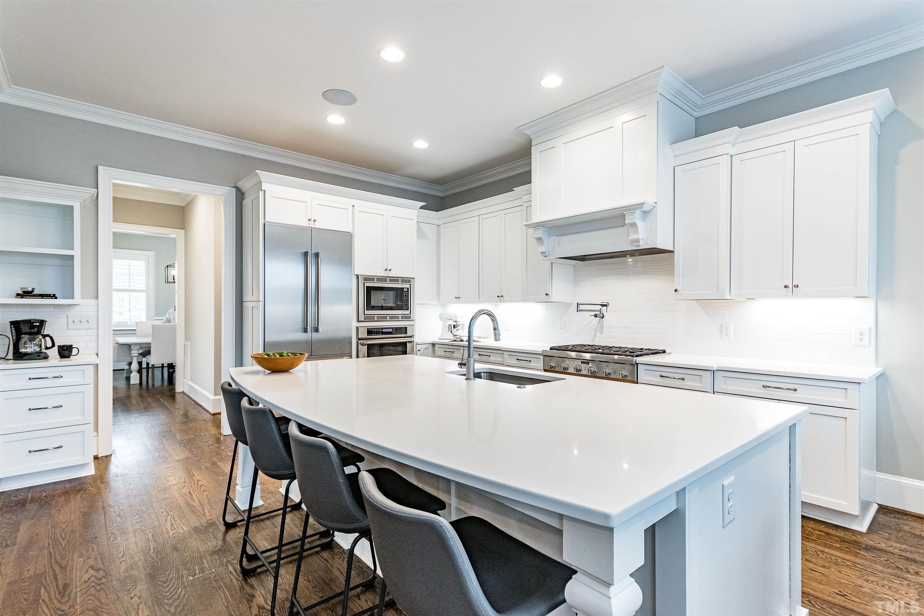 641 Cranbrook Road Raleigh, NC 27609 - Photo 12 of 39 a kitchen with stainless steel appliances a stove a sink a refrigerator white cabinets and couches with wooden floor