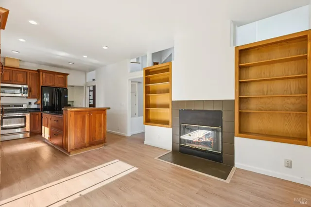 a kitchen with stainless steel appliances granite countertop a refrigerator a sink dishwasher a stove with wooden cabinets and wooden floor