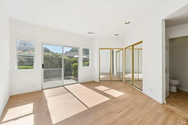 a view of an empty room with wooden floor and windows