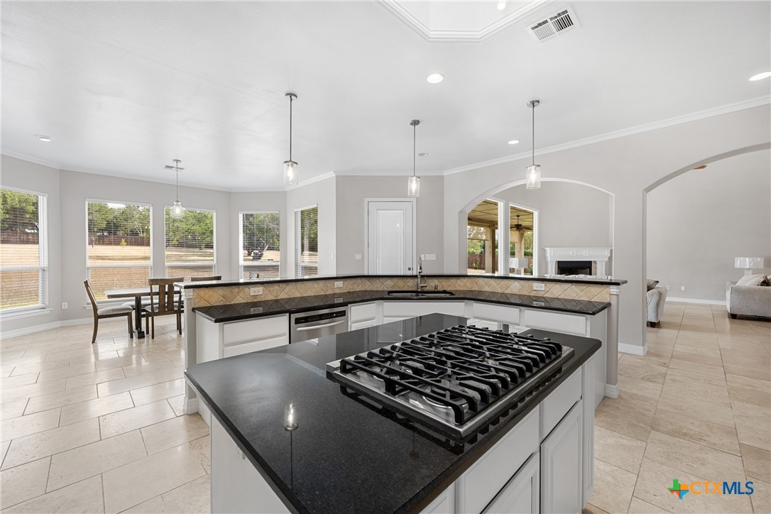 6717 Springwood Court Temple, TX 76502 - Photo 11 of 33 a kitchen with a stove a sink dishwasher and a dining table with wooden floor