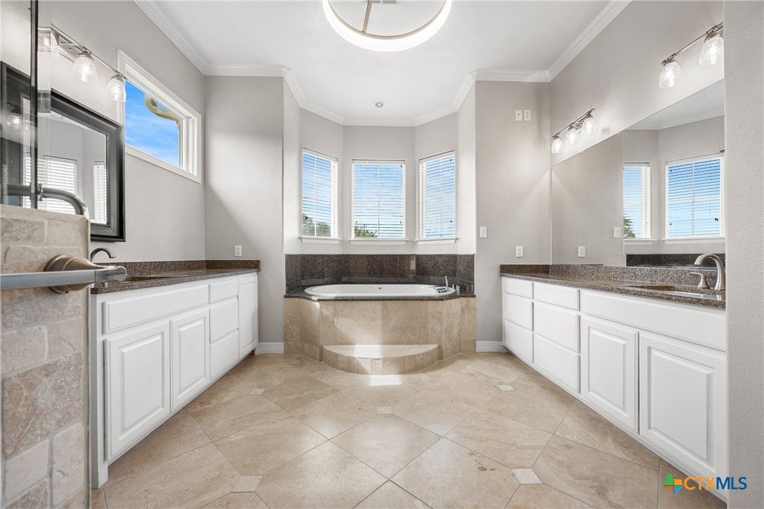 6717 Springwood Court Temple, TX 76502 - Photo 24 of 33 a large bathroom with a granite countertop sink a toilet a mirror and bathtub