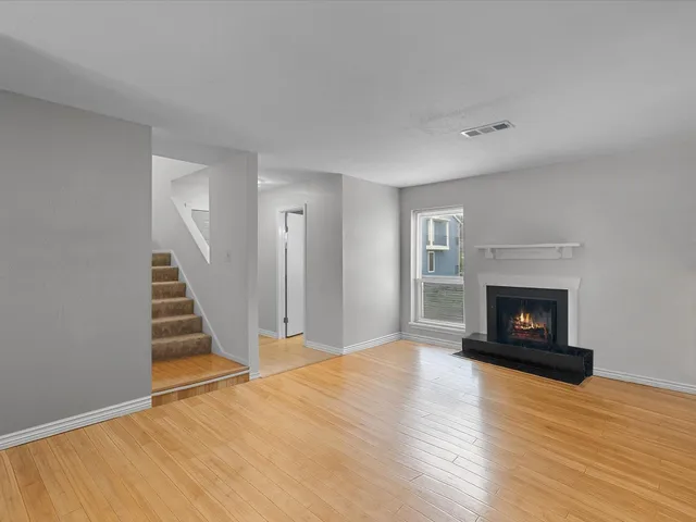 a view of a livingroom with wooden floor and a fireplace