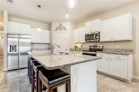 a kitchen with kitchen island granite countertop a stove a sink a refrigerator and a microwave