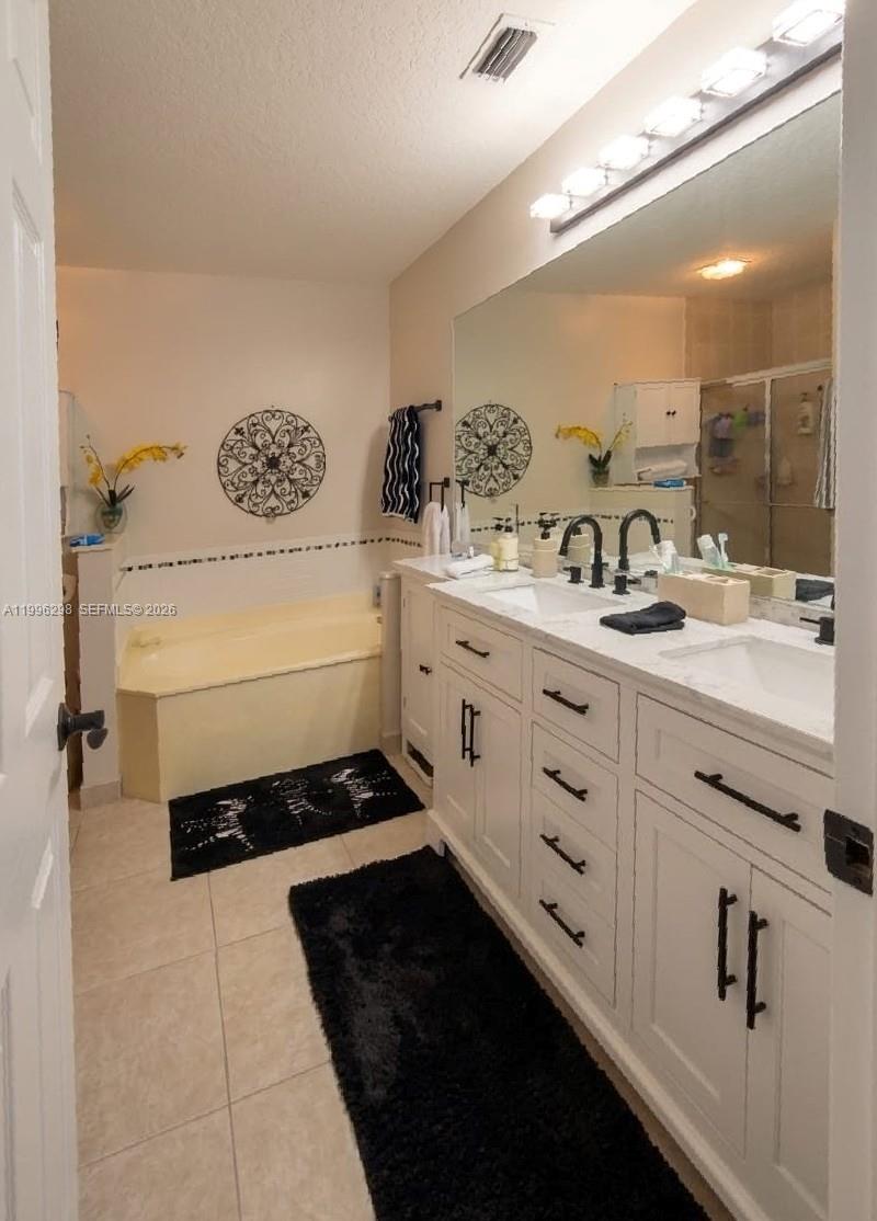 1016 Via Jardin, Unit 1016 Riviera Beach, FL 33418 - Photo 6 of 15 a bathroom with a double vanity sink a mirror and a bathtub