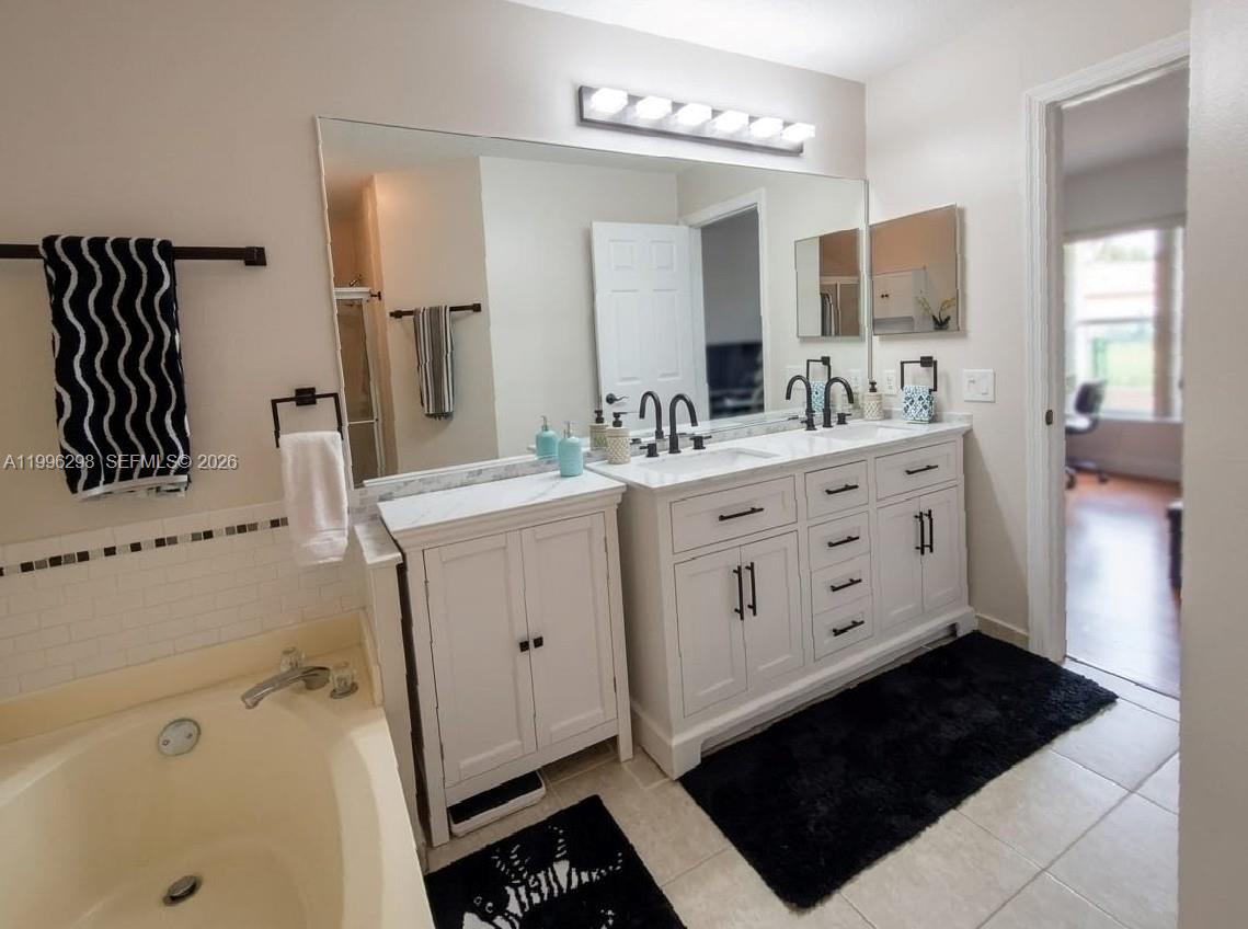 1016 Via Jardin, Unit 1016 Riviera Beach, FL 33418 - Photo 7 of 15 a spacious bathroom with a double vanity sink a mirror and a bathtub