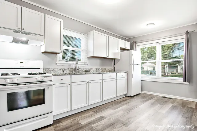 a kitchen with granite countertop white cabinets and white appliances