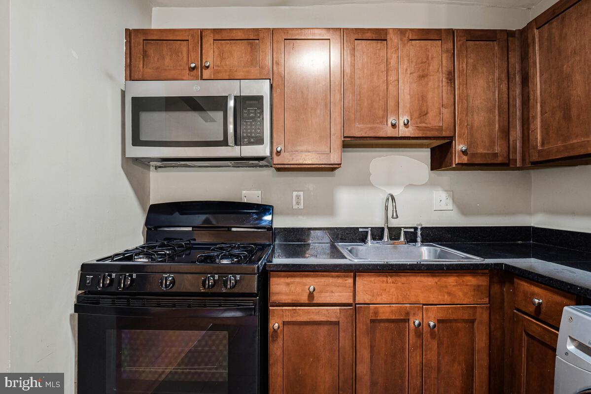 3103 Naylor Road Southeast, Unit 304 Washington, DC 20020 - Photo 11 of 28 a kitchen with granite countertop a stove and a microwave