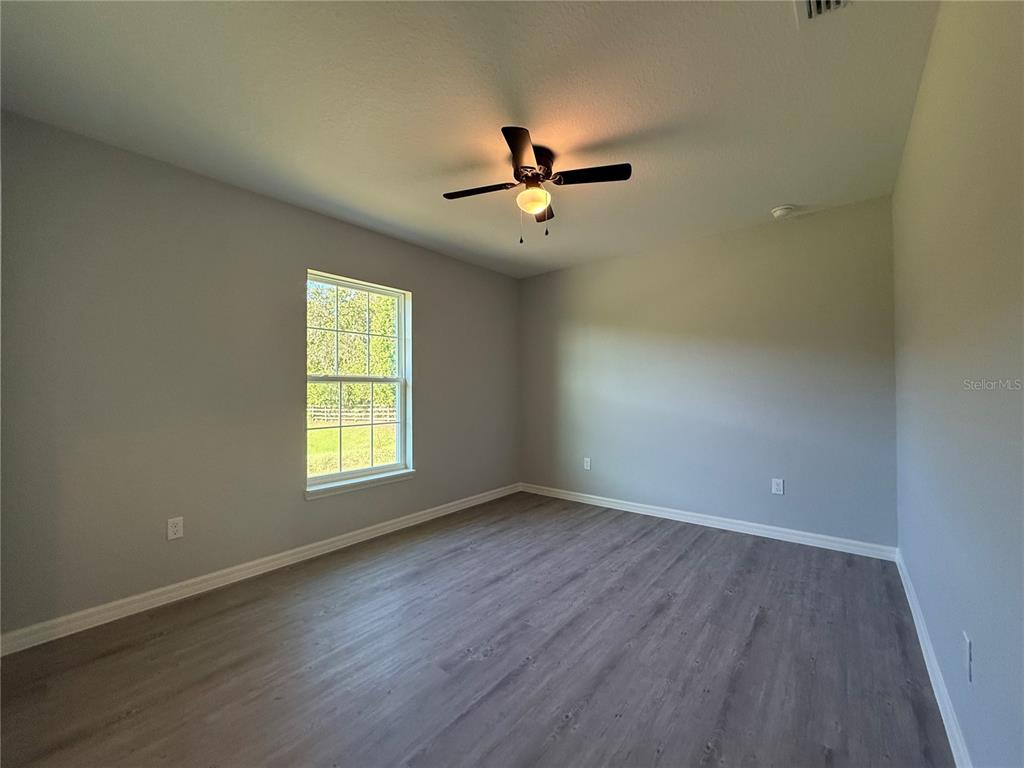19 Northwest 45th Loop Ocala, FL 34475 - Photo 12 of 28 an empty room with wooden floor ceiling fan and windows