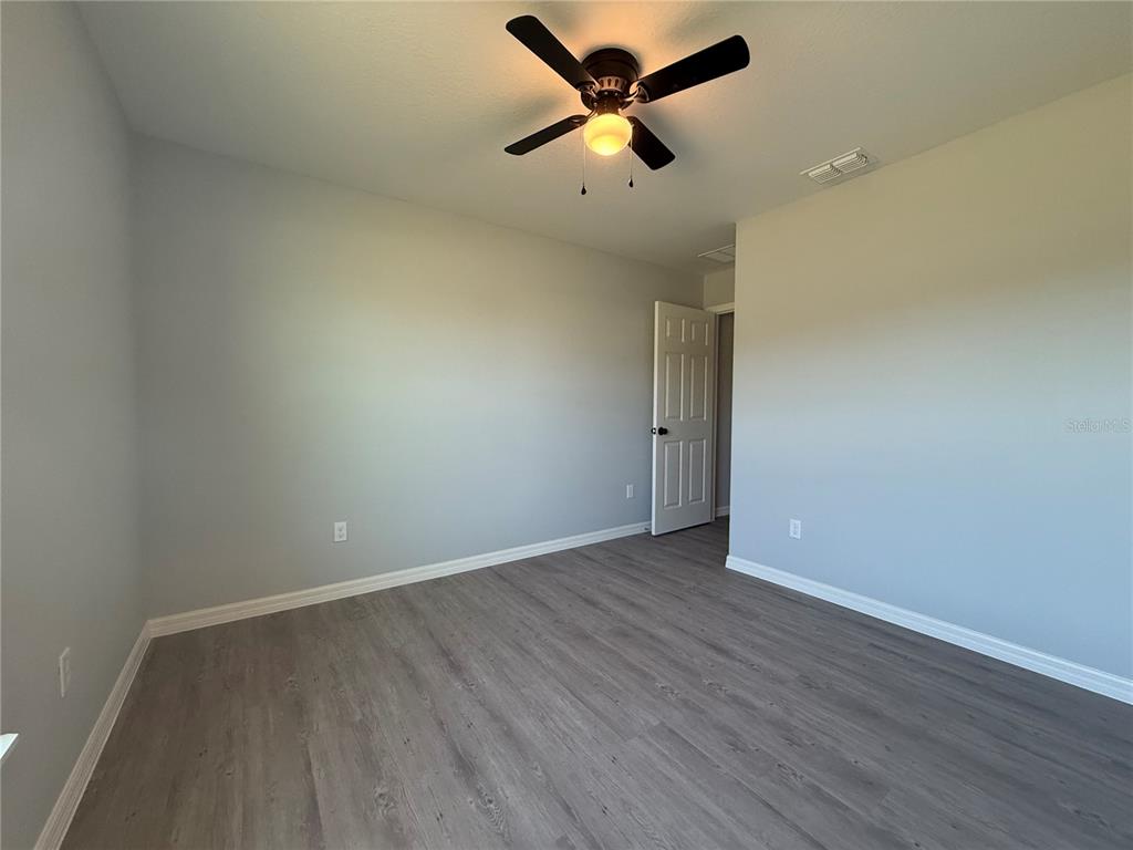 19 Northwest 45th Loop Ocala, FL 34475 - Photo 16 of 28 an empty room with wooden floor and a ceiling fan
