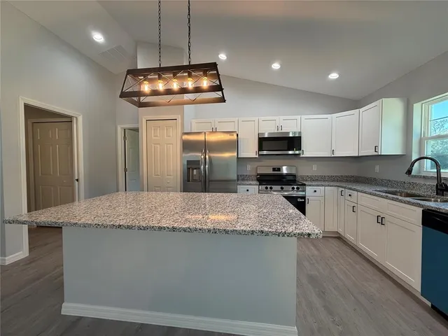 a kitchen with kitchen island granite countertop stainless steel appliances a stove sink microwave and cabinets