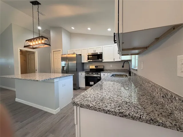 a kitchen with a sink a counter top space appliances and cabinets