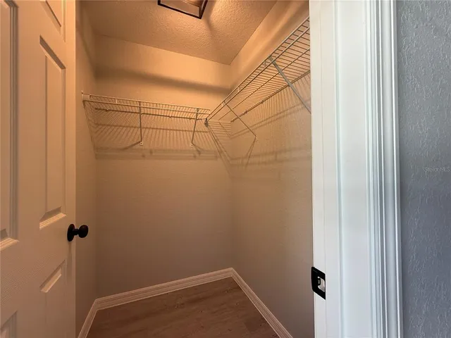 an empty room with wooden floor ceiling fan and windows