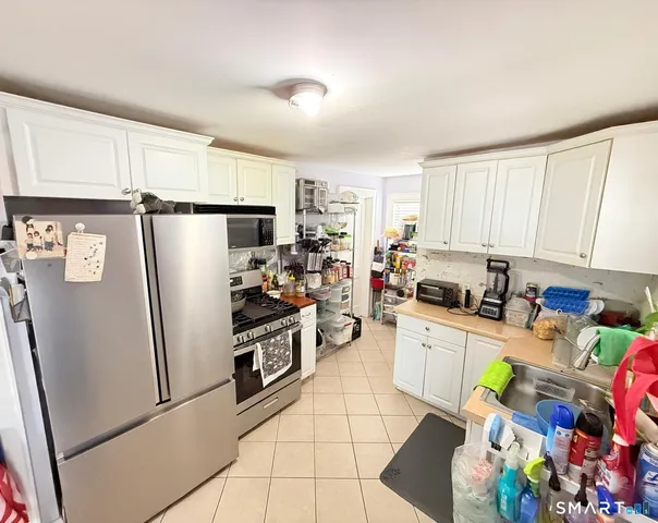 a kitchen with stainless steel appliances a refrigerator sink and white cabinets