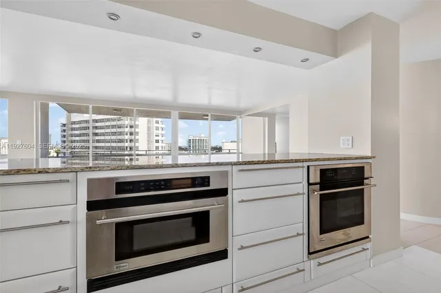 a large white kitchen with granite countertop a large window