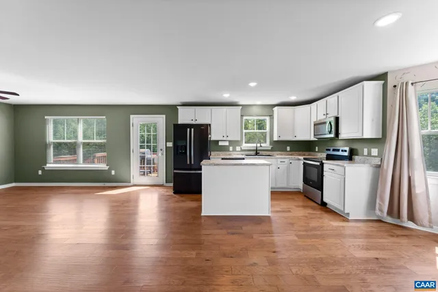 a kitchen with granite countertop a refrigerator oven a sink dishwasher and white cabinets with wooden floor