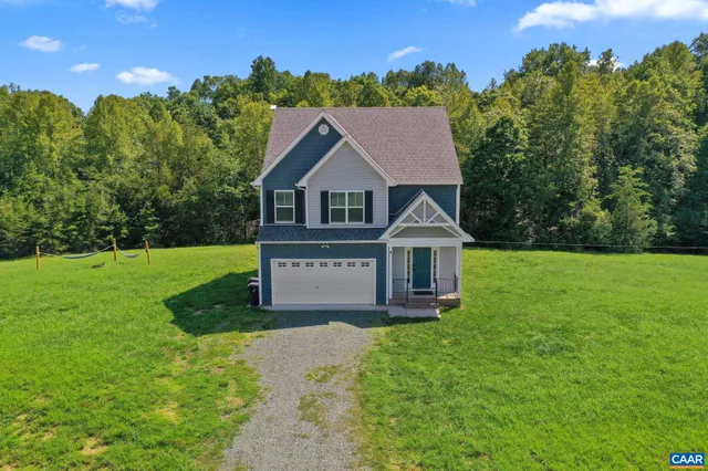 a view of a house with a big yard potted plants and large tree