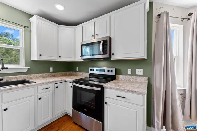 a kitchen with granite countertop white cabinets and white appliances