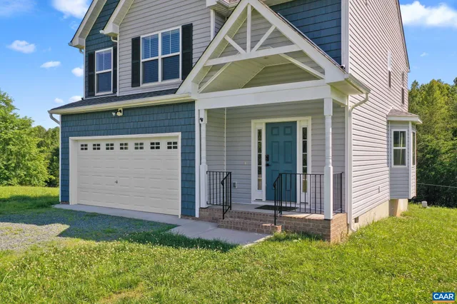 a view of a house with small yard plants and large tree