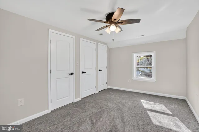 a view of empty room with wooden floor and ceiling fan