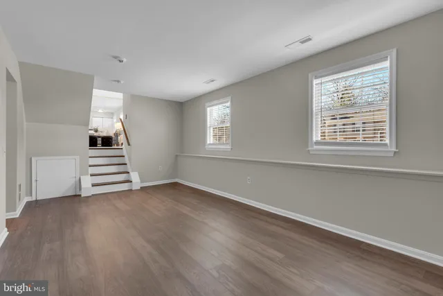 a view of an empty room with wooden floor and window