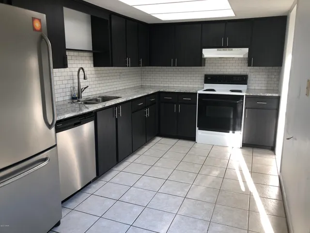 a kitchen with stainless steel appliances granite countertop a stove a sink and a microwave