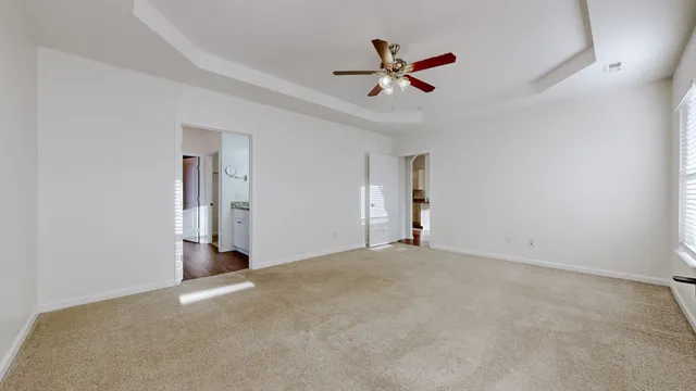 a view of an empty room and chandelier fan