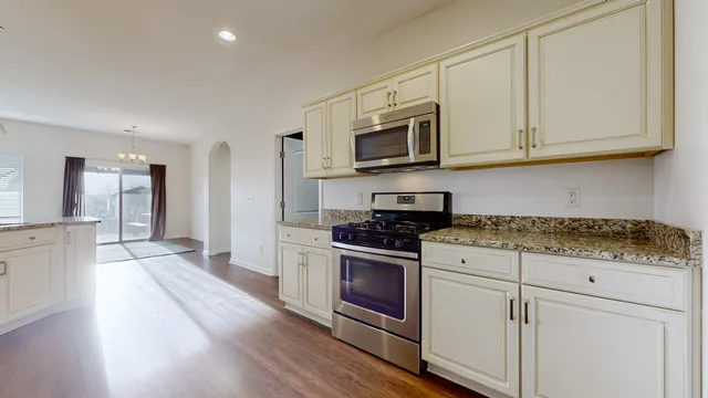 a kitchen with stainless steel appliances granite countertop a stove a sink and a microwave