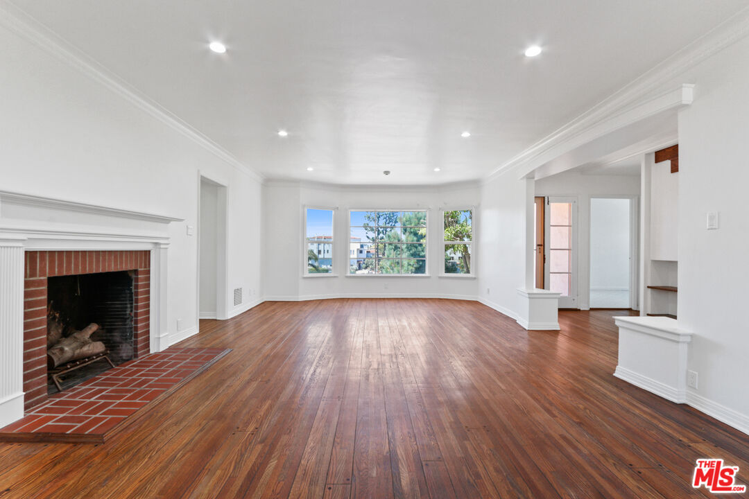 3851 Olympiad Drive View Park, CA 90043 - Photo 11 of 35 an empty room with wooden floor fireplace and windows