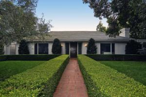 a view of a brick house in front of yard and couple of flower plants