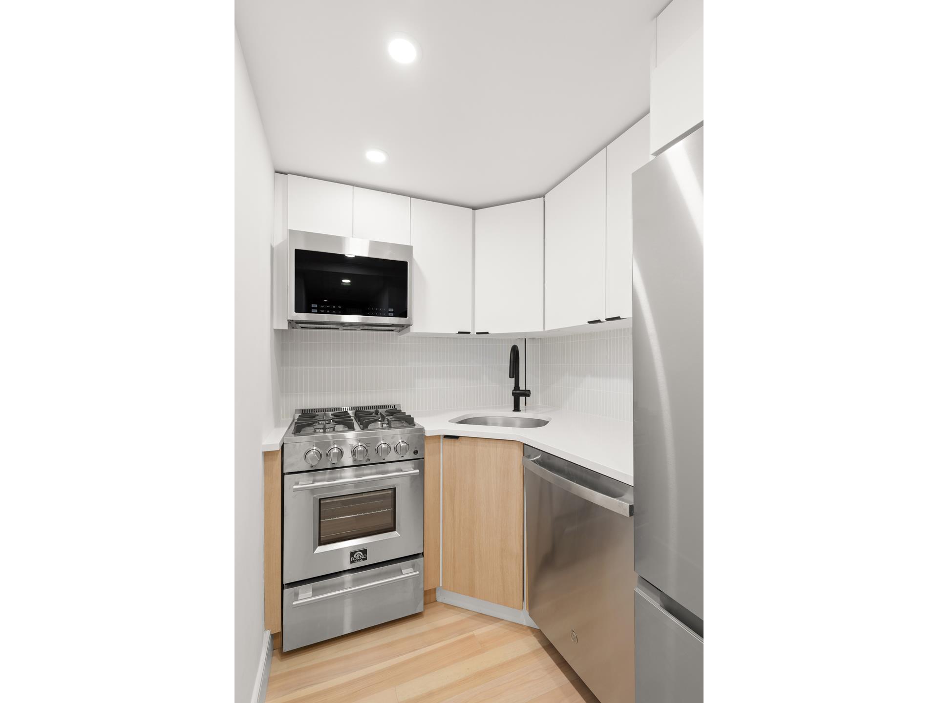 321 East 48th Street, Unit 11H Manhattan, NY 10017 - Photo 4 of 8 a kitchen with a sink and a stove top oven