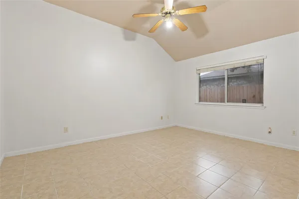 an empty room with a chandelier fan and windows