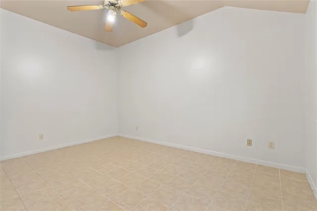 an empty room with a chandelier fan and windows